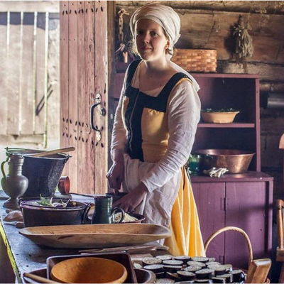 A woman wearing a yellow and black wool dress standing at a table.