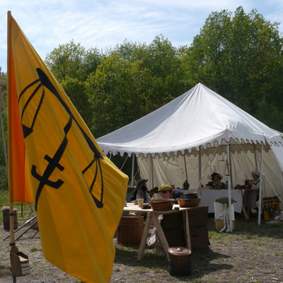 a gold flag flies in front of a large canvas tent.