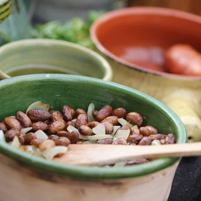 pottery dishes holding various foods sit on a wooden table.